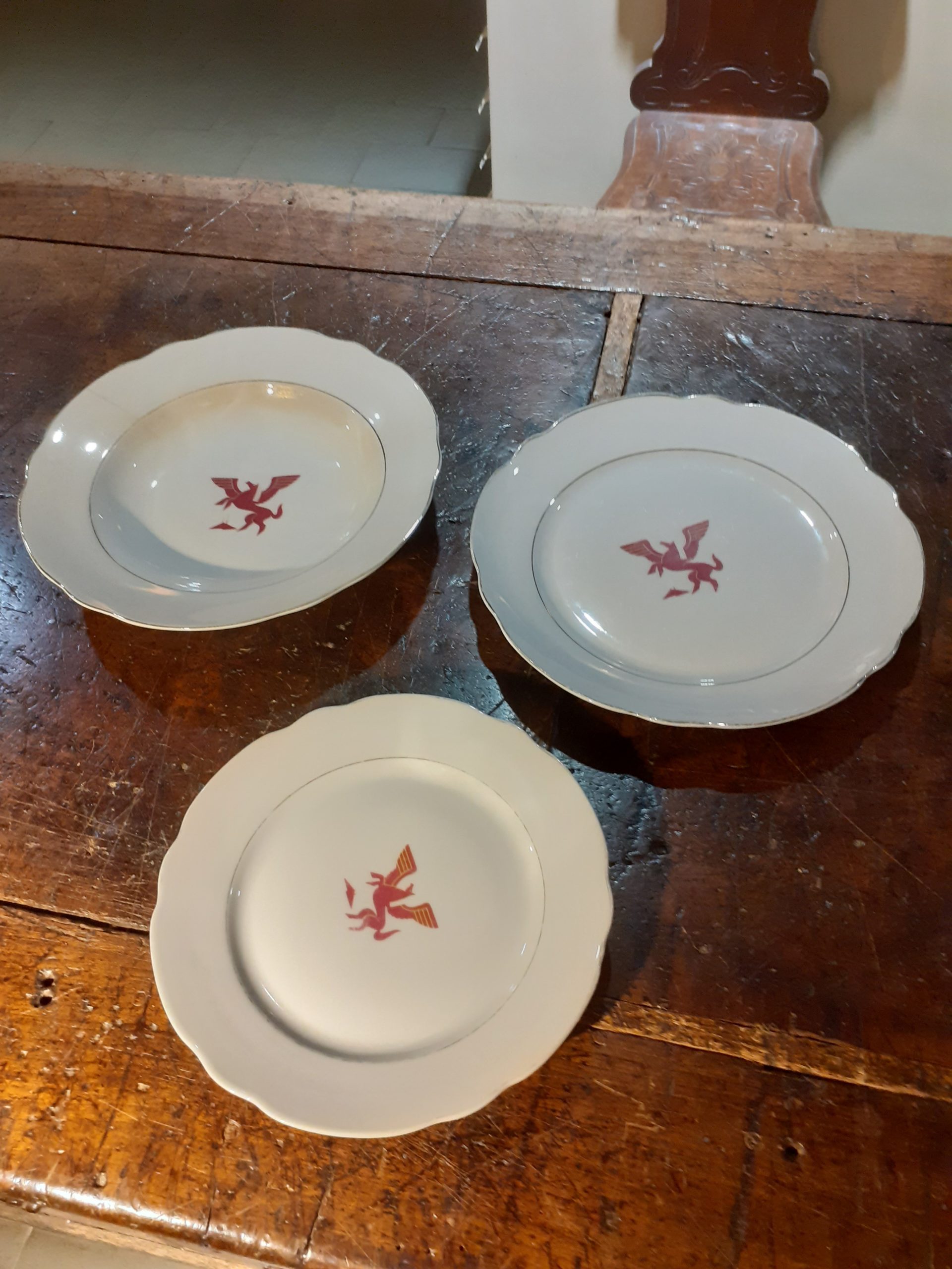 Tre piatti di colore bianco, tutti con un cavallo alato rosso al centro